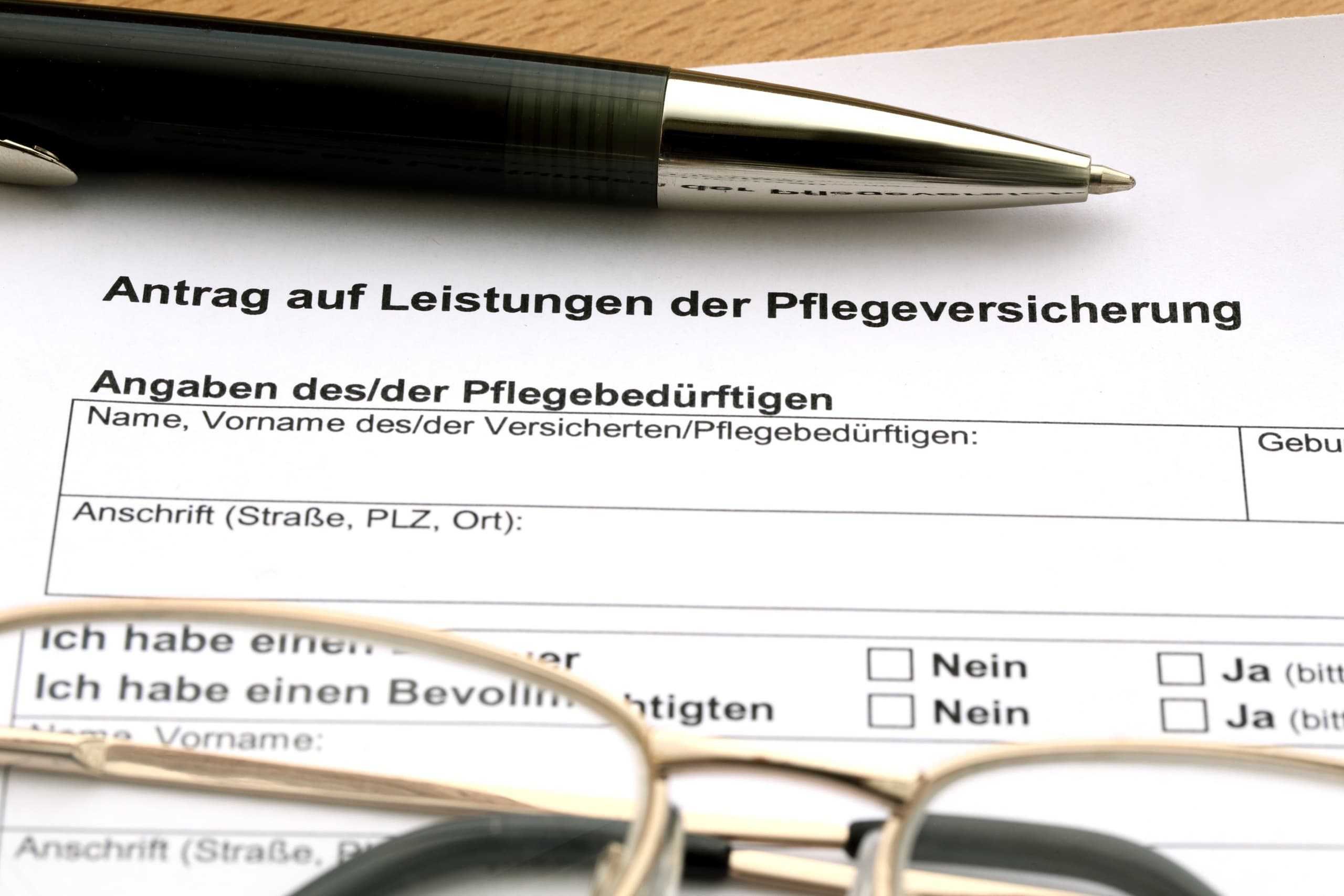 Antragsformular der Pflegekasse mit Stift und Notizen, Antrag auf Wohnumfeldverbesserung
